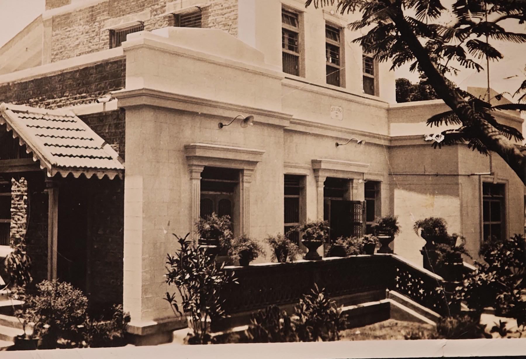 Jer Lodge, a two-storey house at 29 Parsi Colony, Karachi, with a tiled porch and potted plants by the steps.