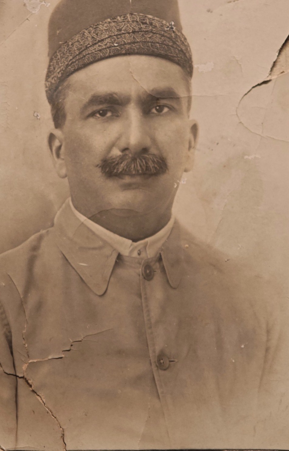 A second, more worn studio portrait of the same man when younger, in a pagri and a pale buttoned jacket.