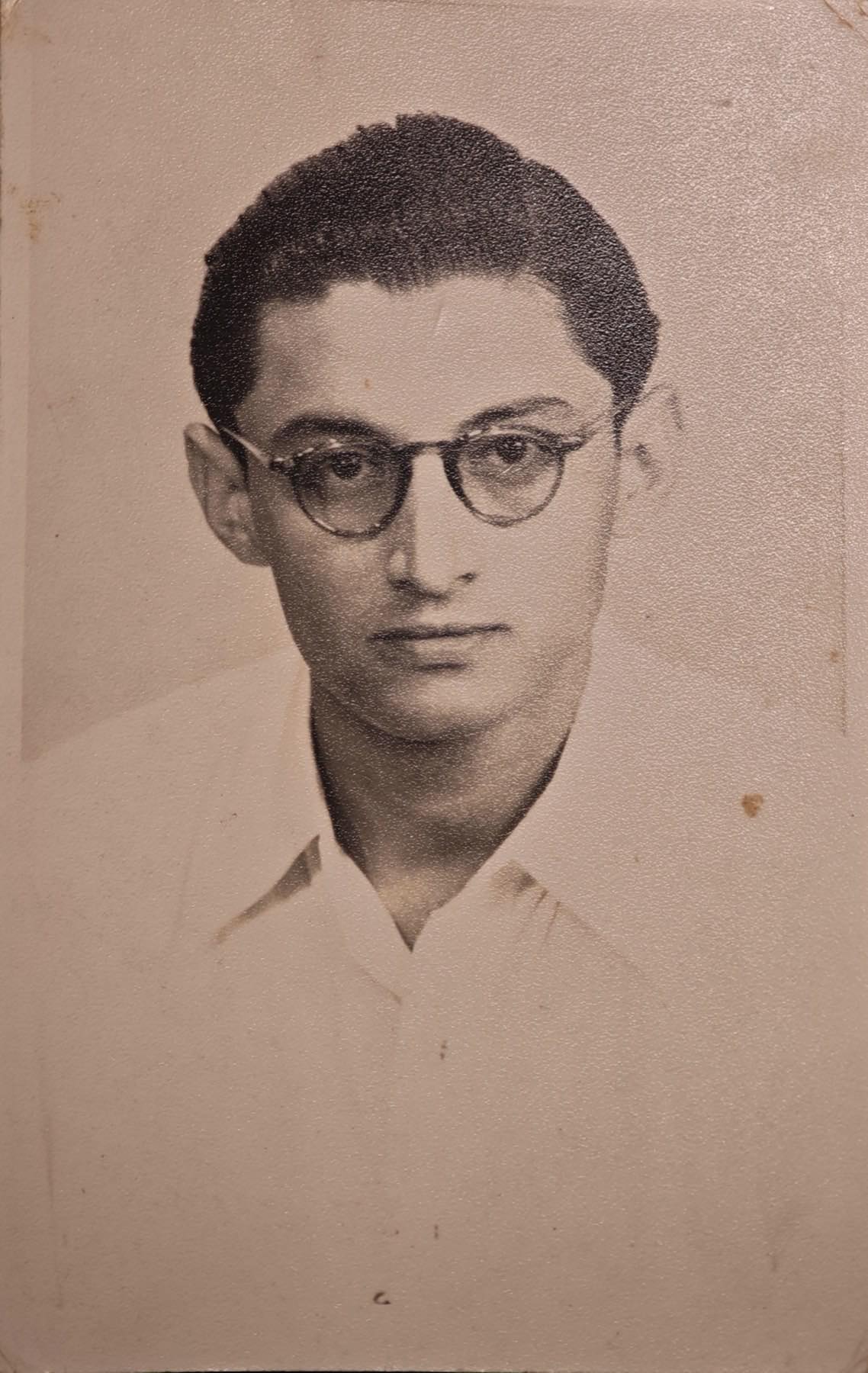 Postcard portrait of Sam Dubash in a white shirt and round wire glasses, about 1955.